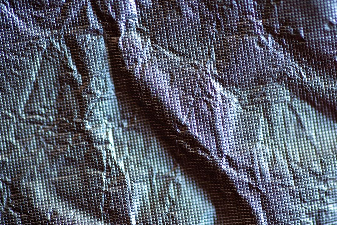 Närbild på ett mörkt, rutmönstrat syntetmaterial för väderbeständiga kepsar.