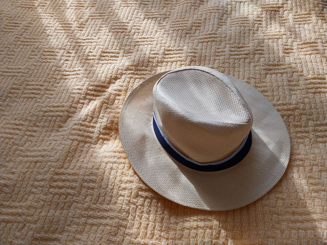 En ljus stråhatt med mörkt band på ett gult strukturerat tyg.